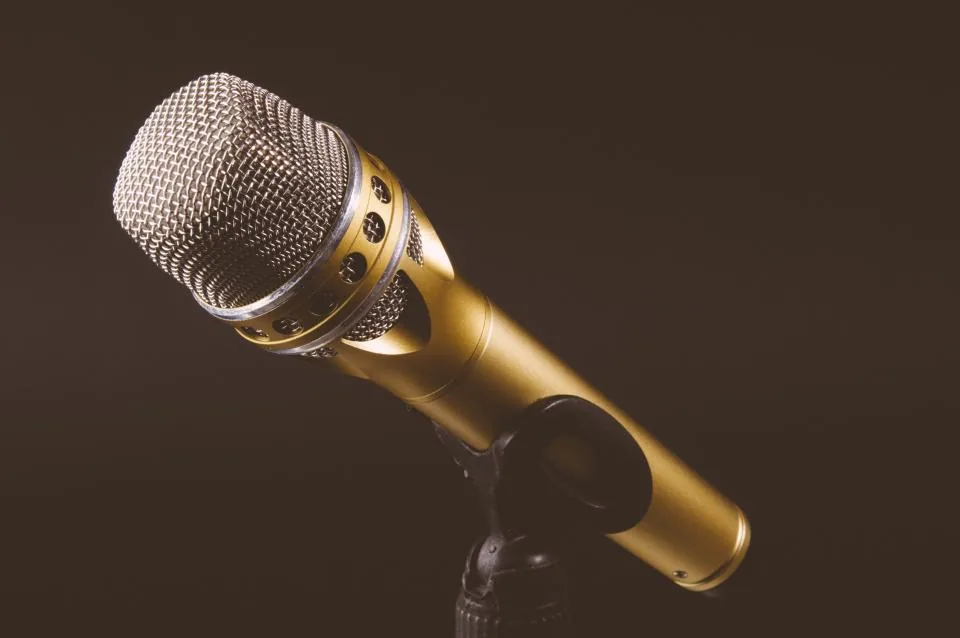 Gold microphone on a stand against a dark background