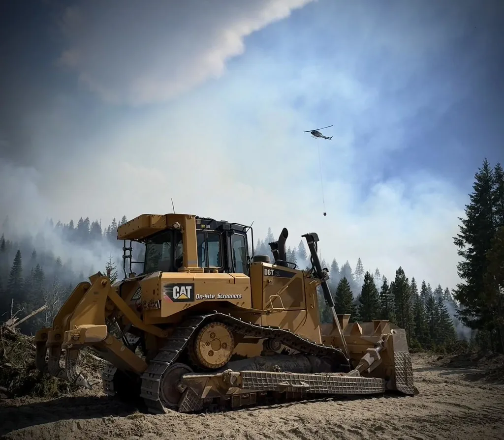 Bulldozer clearing land beside a forest