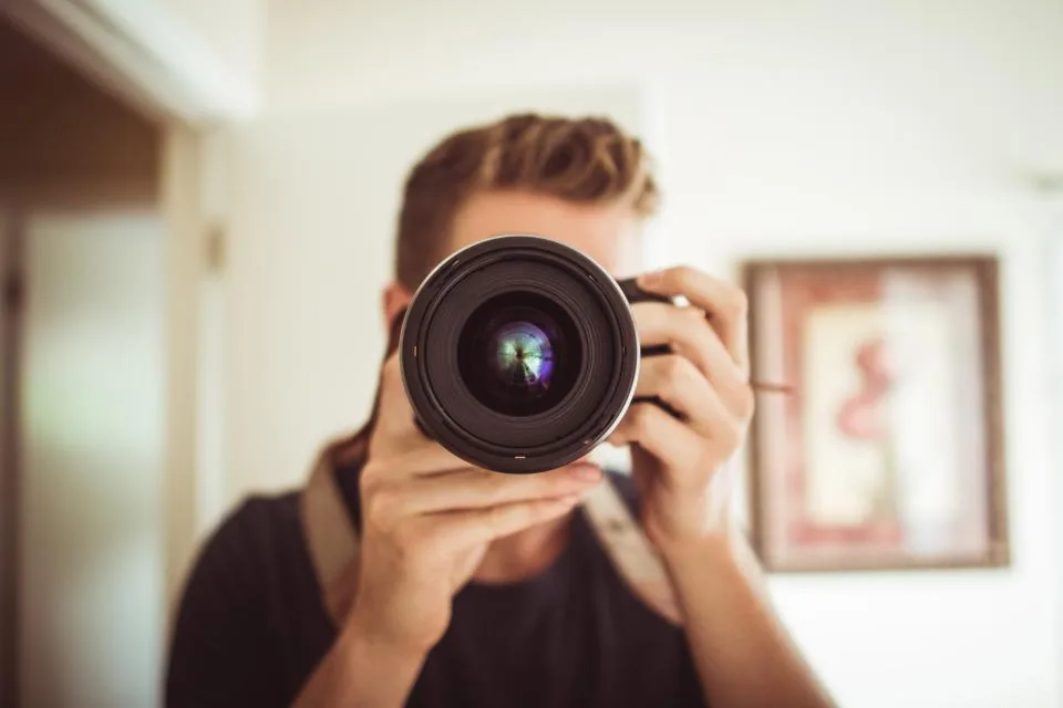 Photographer aiming a camera lens straight at the viewer